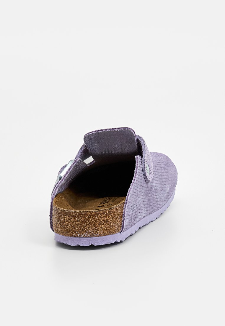 Lavendel-Slipper mit geripptem Stoff-Obermaterial, verstellbarem Riemen, Korkfußbett und strukturiertem Sohle, von hinten auf weißem Hintergrund gezeigt.