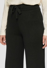 Zwarte gebreide loungebroek met een trekkoord in de tailleband, voorzien van een zachte textuur en een rechte broekspijp. Inclusief zakken.