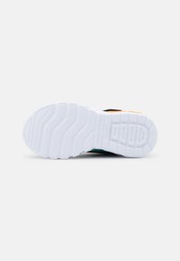 Calzature Skechers con suola in gomma bianca, caratterizzate da un motivo testurizzato per la presa e accenti multicolori nella parte superiore.