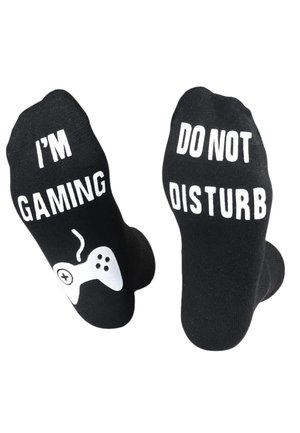 Zwarte katoenen sokken met witte graphics. Aan de ene kant staat "IK BEN AAN HET GAMEN" met een spelcontroller; aan de andere kant staat "NIET STOREN."