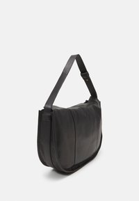 Melnas pleca soma, izgatavota no gludas ādas, ar vienu regulējamu siksnu, izliektu formu un ar rāvējslēdzēju aizdari. Minimālistisks dizains bez redzamām detaļām.