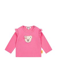 Rosa Langarmshirt mit einem Bärenkopf-Applikation in der Mitte und Rüschendetails an den Ärmeln. Hergestellt aus weichem Baumwollstoff.