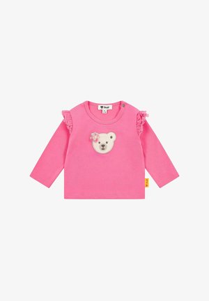 Rosa Langarmshirt mit einem Bärenkopf-Applikation in der Mitte und Rüschendetails an den Ärmeln. Hergestellt aus weichem Baumwollstoff.