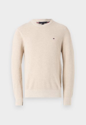 Beige strikkegenser med rund hals, ribbede mansjetter og en liten logo på brystet. Myk tekstur med en klassisk passform.