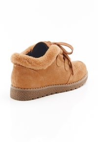 Stivaletti in suede marrone con colletto in pelliccia sintetica, punta rotonda e design con lacci. Presentano una suola in gomma testurizzata per una migliore aderenza.