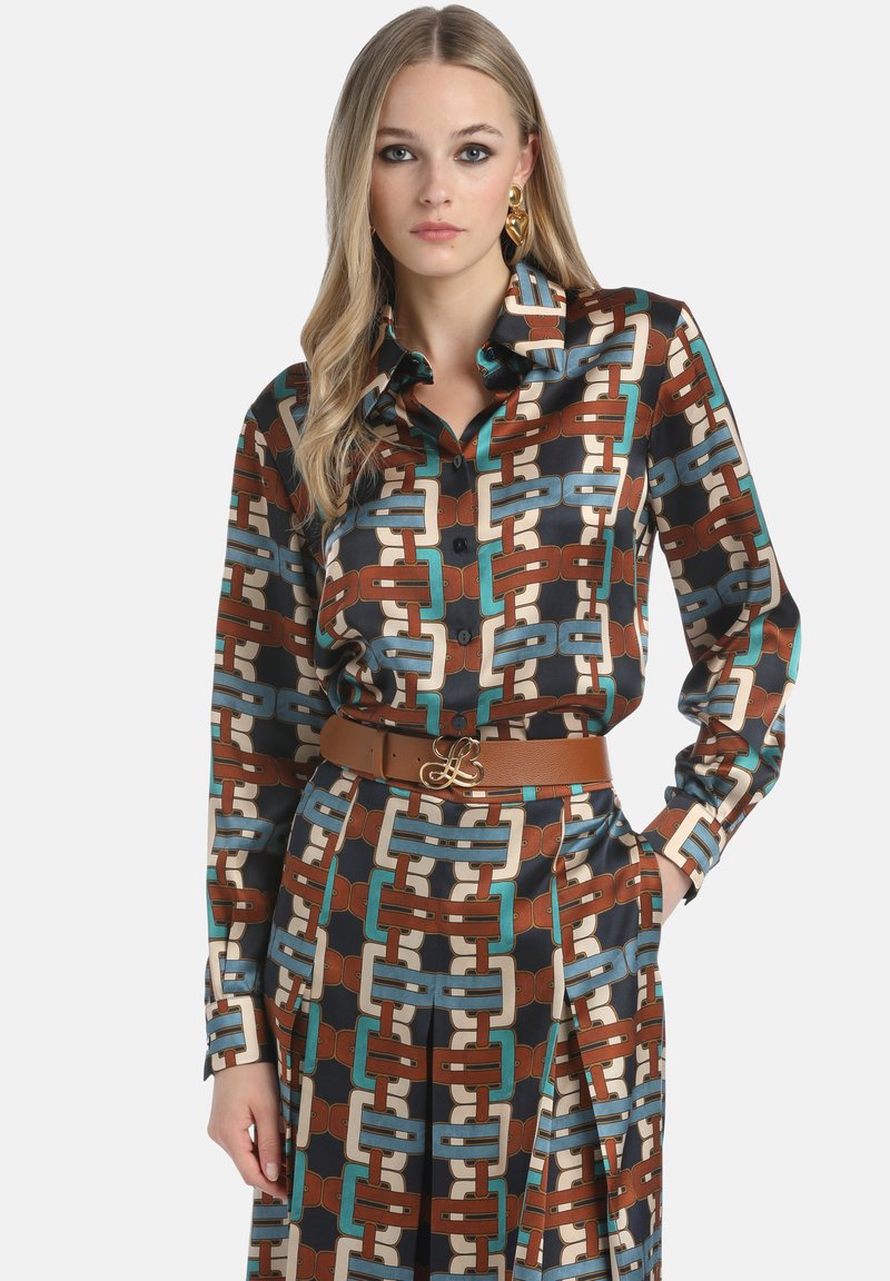 Kuviollinen paita, jossa on ruskea, teal ja kerma beige geometrinen muotoilu, pitkät hihat, nappikiinnitys ja ruskea vyö logokoristeella.