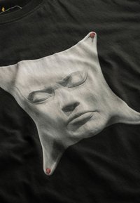 Zwarte katoenen t-shirt met een grijze sculpturale gezichtprint met gesloten ogen en een textuur, geaccentueerd met rode randen.