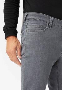Graue Jeans aus Denim mit geradem Schnitt, ausgestattet mit frontalen Taschen, einem eleganten Design und dezentem Stitching. Der Stoff zeigt eine leichte Textur und Strapazierfähigkeit.