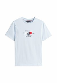 Camiseta de algodón azul claro con un gráfico en el frente que incluye la palabra "HILFIGER", un emblema y el año de establecimiento "EST. 1985". Mangas cortas.