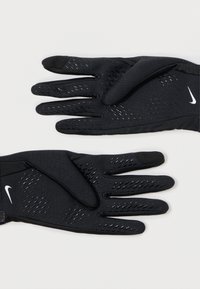 Zwarte sporthandschoenen gemaakt van rekbaar materiaal, met een gestructureerde grip op de handpalmen en ademende mesh-details op de achterkant. Nike-logo aanwezig.