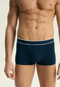 Granatowe bokserki z kontrastującą białą gumką. Wykonane z miękkiej tkaniny, z dopasowanym krojem i bez widocznych wzorów ani elementów metalowych.