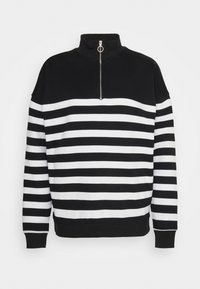 Pulóver a rayas en blanco y negro con un alto cuello y un cierre de media cremallera en la parte frontal. Está hecho de una tela suave, con mangas largas y puños acanalados.