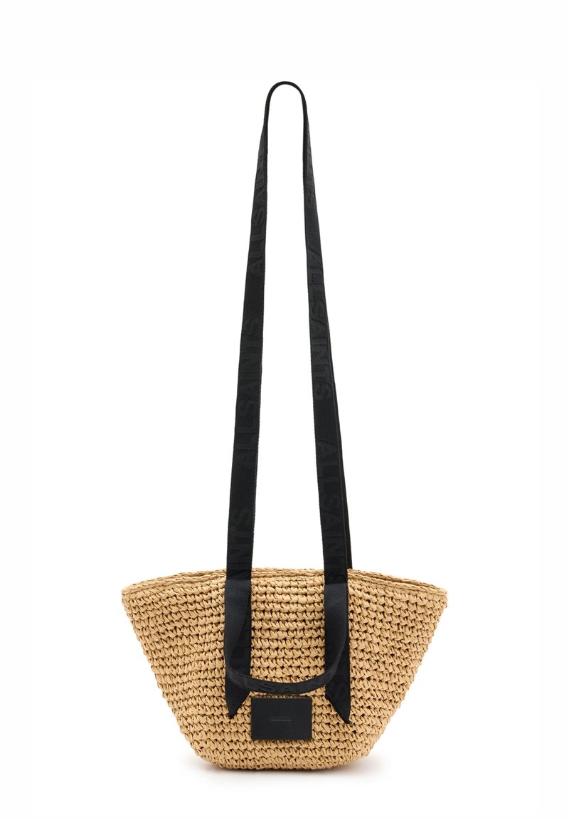 Sac à main en paille tressée avec une large bandoulière en tissu noir et une étiquette noire à l'avant.