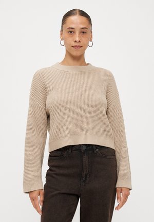 Strikket genser i lys beige med teksturert mønster og rund halslinning. Kuttet lengde og lange ermer. Kombinert med mørke høyt midje jeans.