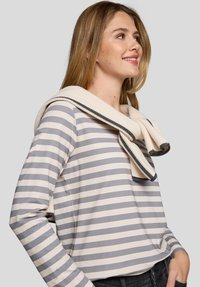 Langarm gestreiftes Hemd in Creme und Grau mit einem strukturierten Strickschal, der um den Hals drapiert ist. Verfügt über einen Rundhalsausschnitt und einen lässigen Schnitt.