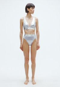 Ezüst metál bikiniszett, mély V-nyakú melltartóval és magas derekú alsóval. Sima textúrájú, mintázat nélkül.