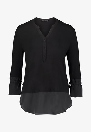 Zwarte blouse met lange mouwen, drie knopen bij de V-hals, geplooide manchetten met strikjes en een halfdoorzichtige stofpaneel aan de zoom.
