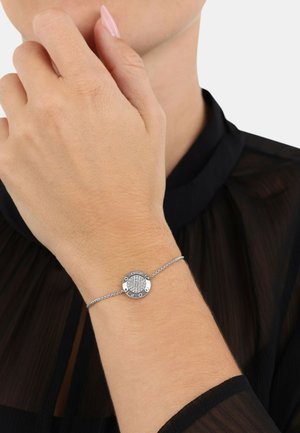 Pulsera de plata con un centro redondo que presenta una superficie texturizada y acentos grabados. Diseño de eslabones con un brillo sutil.