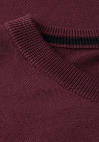 Pull en tricot bordeaux avec un col côtelé et un tissu texturé, présentant des zones lisses contrastant avec le design côtelé.