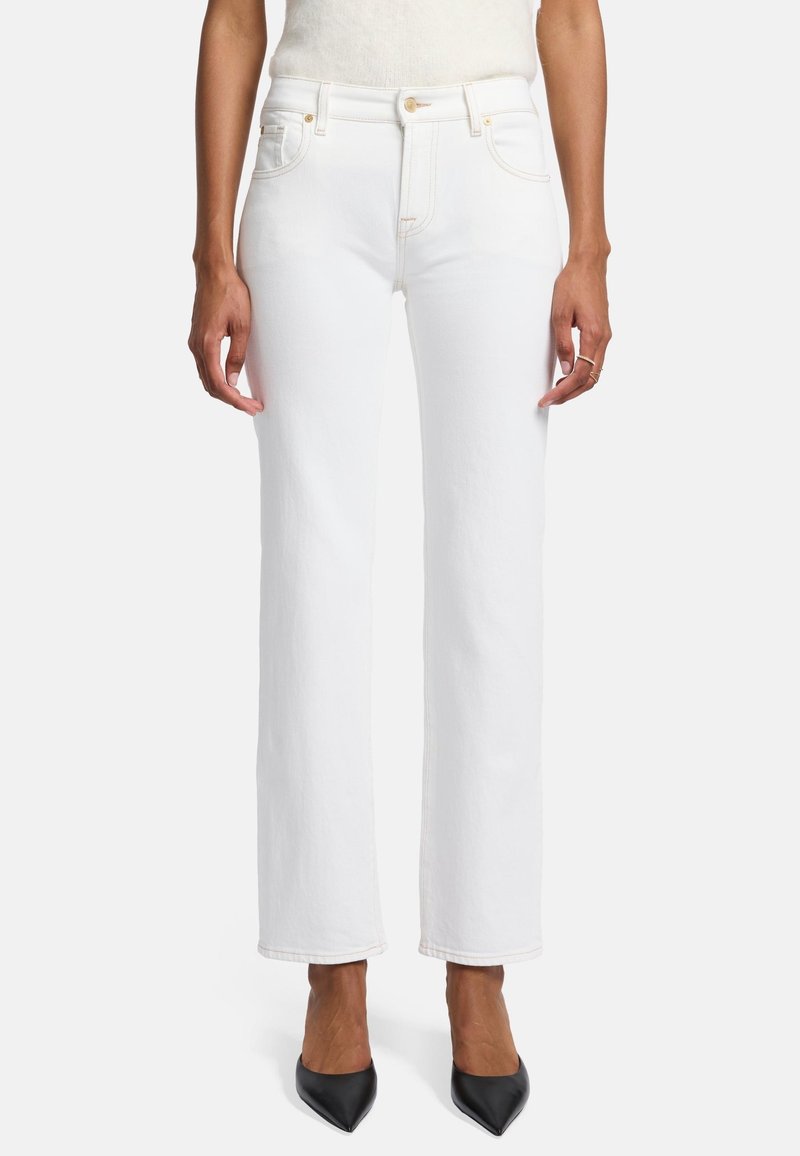 Białe dżinsy straight-leg z czterema kieszeniami, złotymi akcentami i kontrastowymi szwami, w połączeniu z czarnymi szpilkami w szpic.