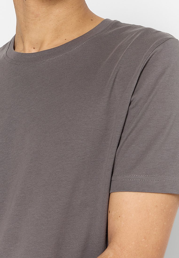 T-shirt grigia in cotone con collo rotondo, maniche corte e una texture liscia. Presenta cuciture minime e una vestibilità comoda.