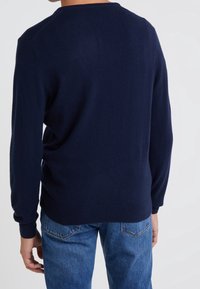 Maglione in maglia blu navy con maniche lunghe, polsini e orlo a coste. Presenta un collo rotondo e una consistenza liscia e morbida.