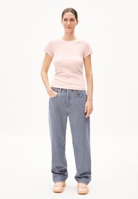 Lichtroze geribde t-shirt met korte mouwen, gecombineerd met loszittende blauwe spijkerbroeken. De outfit heeft een ontspannen silhouet en zichtbare zakken.