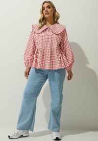 Rosa rutig blus med stor krage, knäppning fram och peplummidja. Parat med ljusblå utsvängda jeans och vita sneakers.