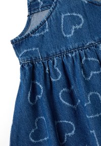 Denimkleid mit blauer Stofffarbe, die mit herzförmigen Mustern in einer helleren Nuance versehen ist, geraffter Taille mit Falten und ärmellosem Design.
