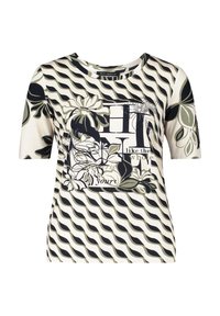 Short-sleeve t-shirt in cream featuring black and olive green wave patterns, floral graphics, and text design. Soft, stretchy fabric.