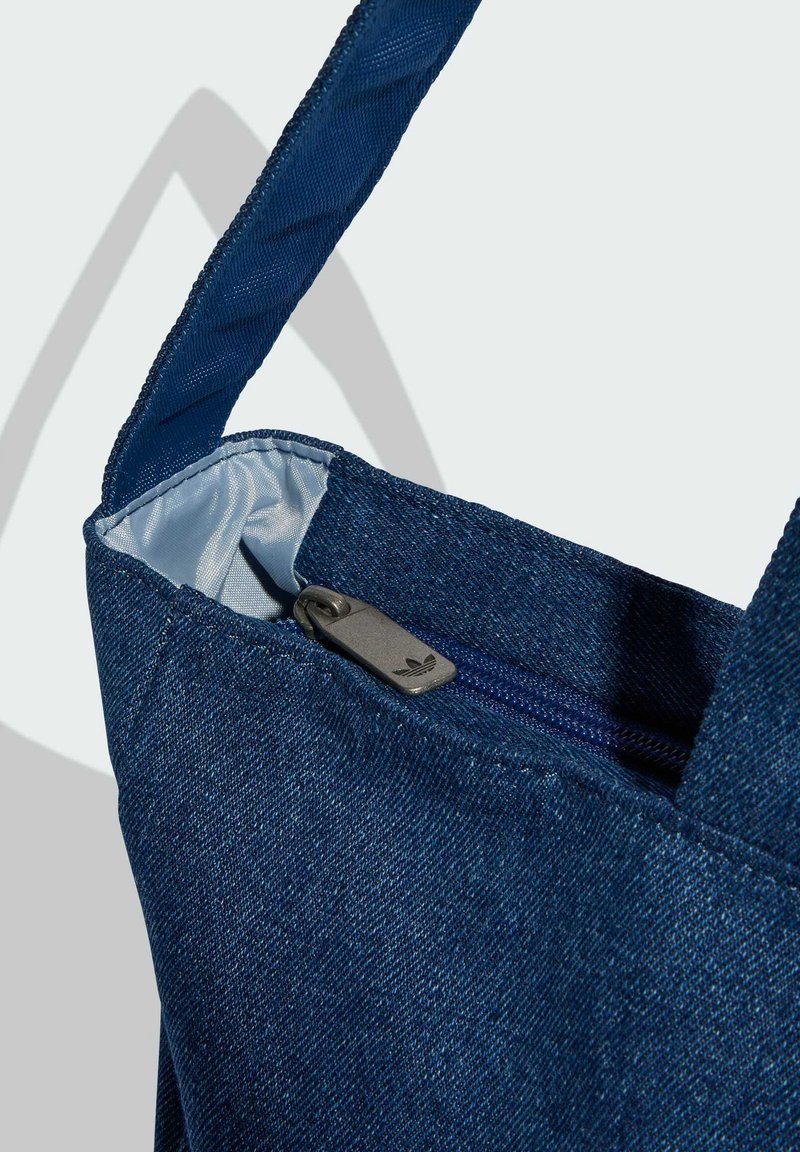 Denim tote bag with a dark blue color, featuring a silver zipper pull, and a smooth lining inside. Sturdy carrying straps included.
