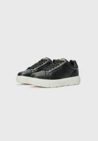 Zwarte leren sneakers met een gladde afwerking, getextureerde zwarte veters en een contrasterende witte rubberen zool. Kenmerkt zich door een slanke, ronde vorm.