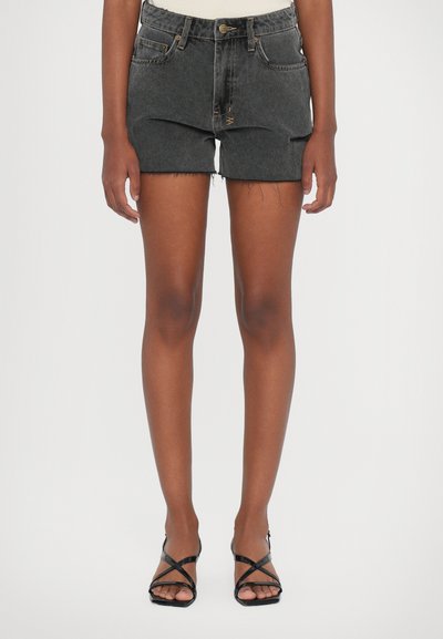 Donkergrijze denimshorts met rafelende zoom, vijf zakken en een knoopsluiting. Draagt het met zwarte sandalen met bandjes, wat de benen en schoenen toont.