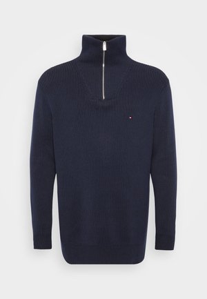 Navy ribbed sweater with a high collar and half-zip closure. Features a small logo accent on the chest. Crafted from textured fabric.