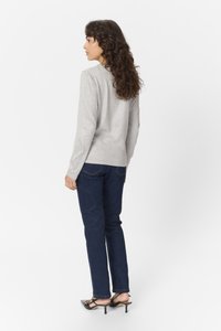 Šedý dlouhý rukáv top s kulatým výstřihem, spárovaný s tmavě modrými džíny a černými vyššími botami. Hladká tkanina a úzký střih.