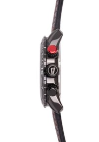 Juodas laikrodis su apvalia dėže, turintis raudoną mygtuką ir karūnėlę. Rudas odinis dirželis su kontrastingomis siūlėmis, tekstūruota paviršius ant dėžutės šono.