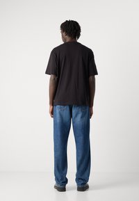 Black cotton t-shirt with short sleeves, paired with loose-fit blue denim jeans featuring a classic five-pocket design and subtle stitching.