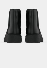 Μαύρες μποτες αστραγάλου με λείο συνθετικό άνω μέρος, στρογγυλή μύτη και υ textured καουτσούκ σόλα. Ορατή ραφή στο πίσω μέρος του άξονα.