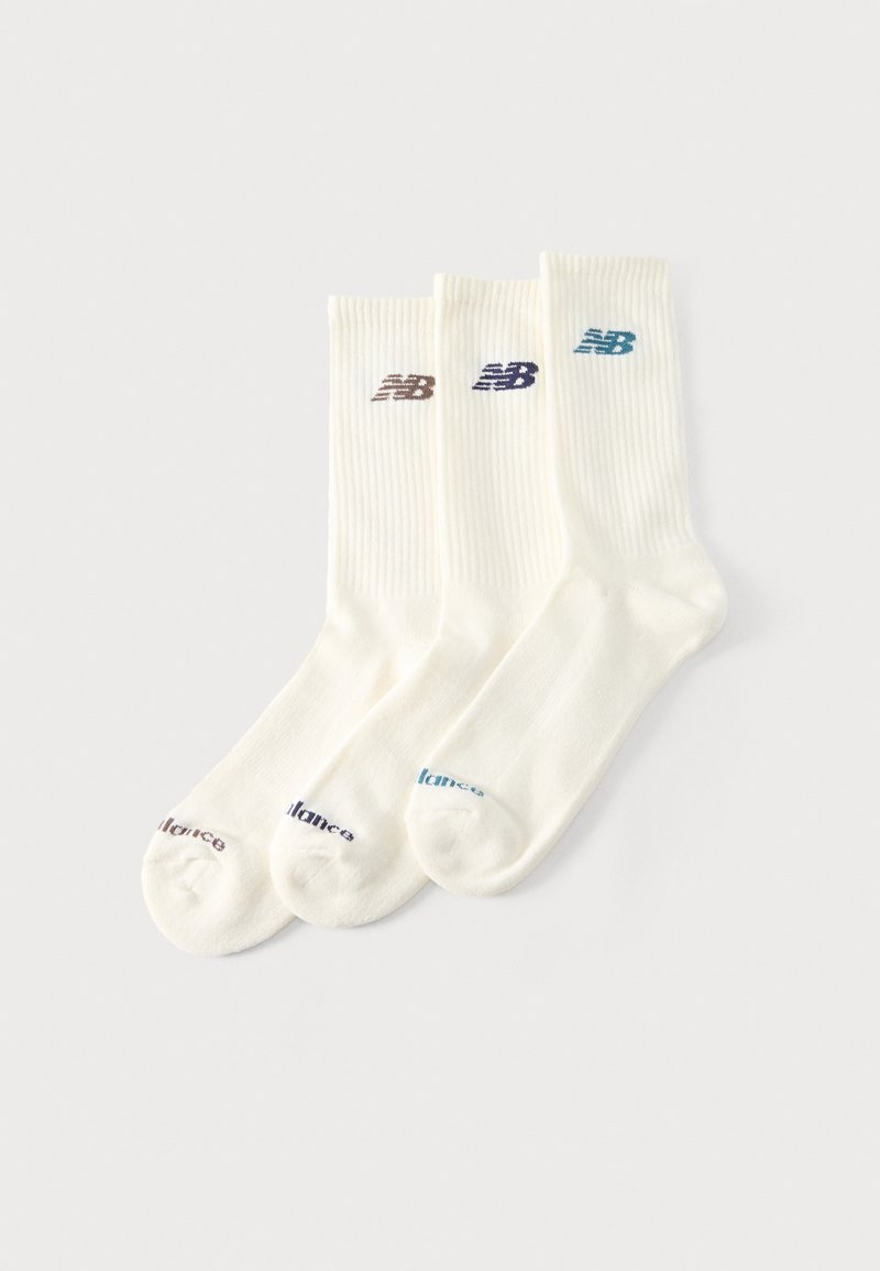 Τρία ζευγάρια λευκές κάλτσες με ριμπ μανσέτες, η κάθε μία με διαφορετικό χρωματιστό λογότυπο "NB" κοντά στο πάνω μέρος και αντίστοιχο κείμενο στα δάχτυλα.