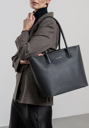 Zwarte leren tote bag met een textuurafwerking, voorzien van twee stevige handvatten en een minimalistisch design. Gouden logo-accent aan de voorkant.