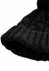 Bonnet en tricot noir avec un bord côtelé et un motif de câble texturé, doté d'un pompon rond sur le dessus. Fil doux et épais.