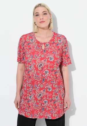 Túnica roja de paisley con mangas cortas y un detalle de escote en forma de ojal. Presenta patrones florales y de paisley multicolores en toda su superficie.