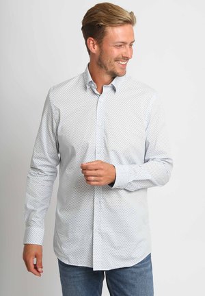 Overhemd met knopen in lichtblauw met een herhalend honingraatpatroon, lange mouwen en een kraag. Draagt bijpassende blauwe spijkerbroek.