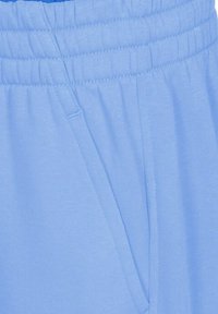 Pantalones deportivos de color azul claro hechos de una tela suave. Cuentan con una cinturilla elástica, bolsillos laterales y una textura suave con detalles de costura sutiles.