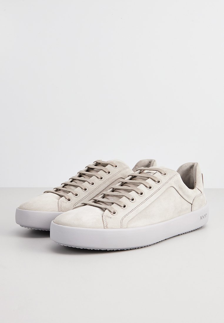 Beżowe zamszowe trampki z okrągłym noskiem, płaską gumową podeszwą i minimalistycznym wzornictwem. Posiadają szare sznurówki i detale w postaci stębnowania po bokach.