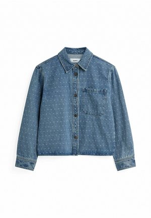 Denim jakk, millel on nupuvälik, krae, rinnatasku ja helesinise täppmustriga tume sinine aluspind. Pikad varrukad.