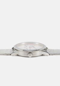 Reloj con correa de malla plateada, caja redonda, cristal transparente y una esfera blanca que presenta marcadores de hora minimalistas y una corona en el lateral.