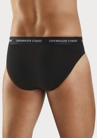 Sorte bomullstruser med en myk, elastisk linning som har "COPENHAGEN STUDIOS" i hvit tekst. Jevn tekstur og klassisk snittdesign.