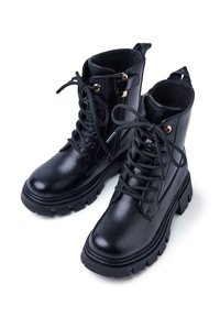 Stivaletti in pelle nera alla caviglia con punta arrotondata, stringhe davanti e cerniera laterale. Presentano una suola spessa con battistrada e accessori in metallo dorato.