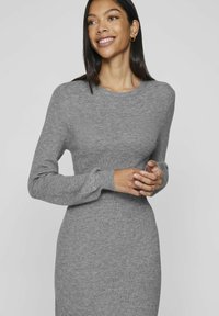 Abito grigio a coste con maniche lunghe e scollatura rotonda, caratterizzato da una silhouette aderente e una texture liscia. Nessun motivo o hardware notevoli.